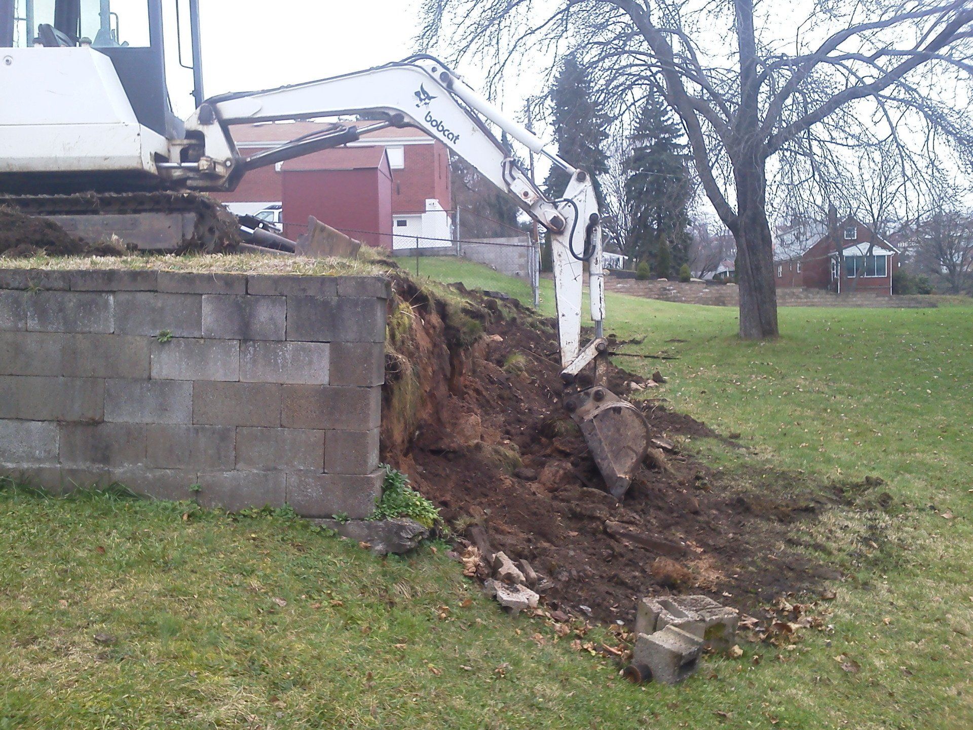 A white excavator is digging a hole in the grass