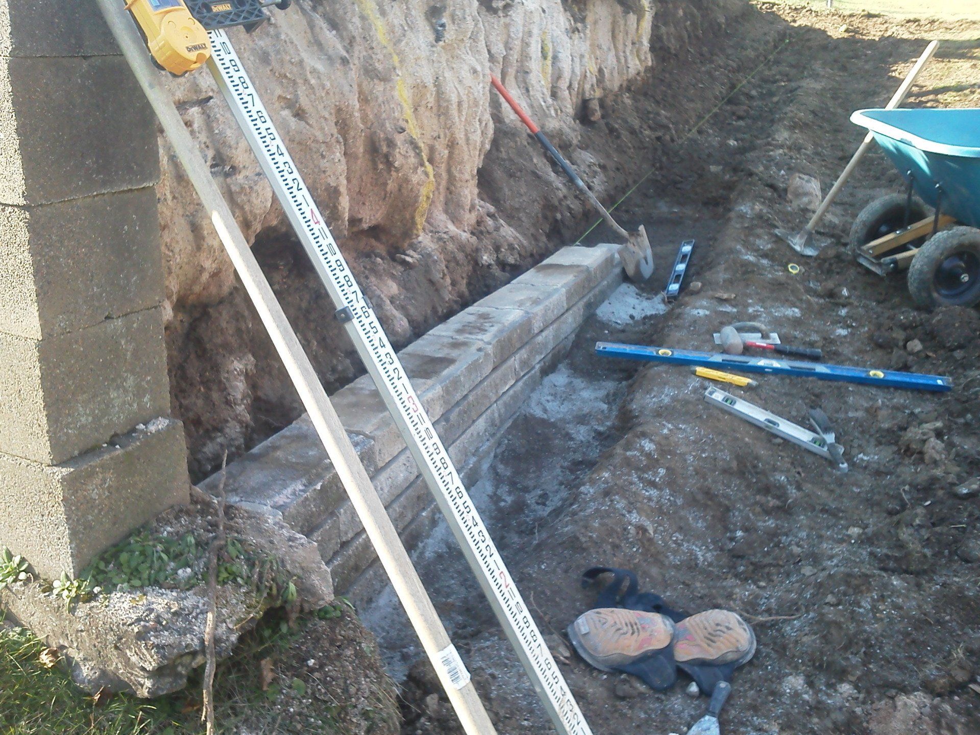 A brick wall is being built next to a wheelbarrow