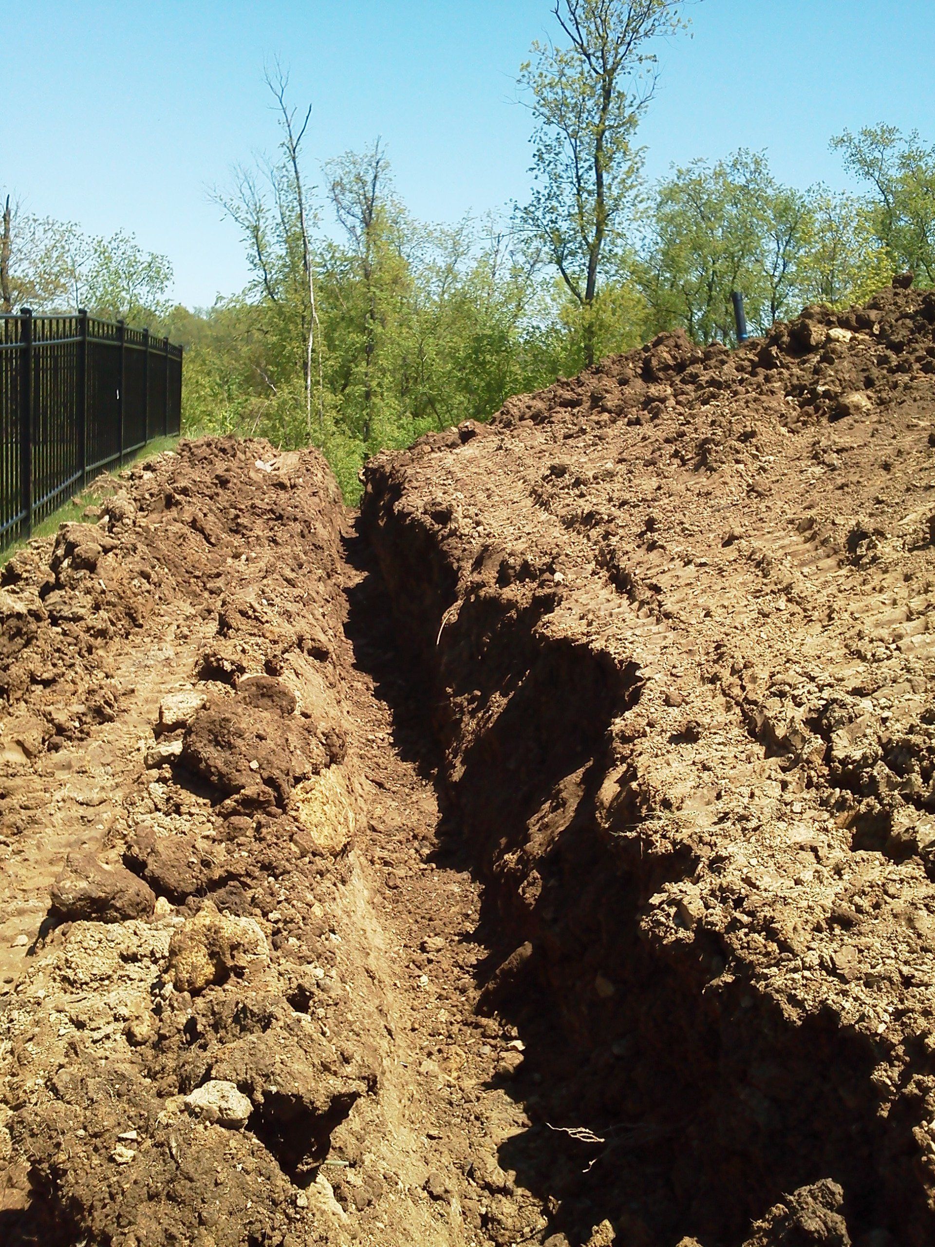 A large pile of dirt with a fence in the background