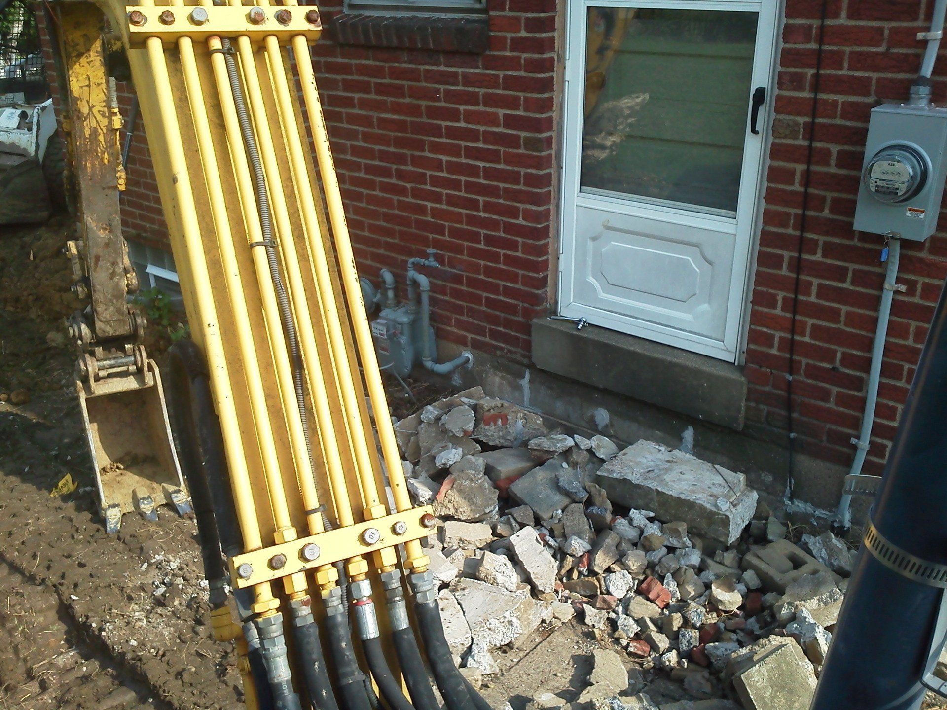 A brick house with a yellow excavator in front of it