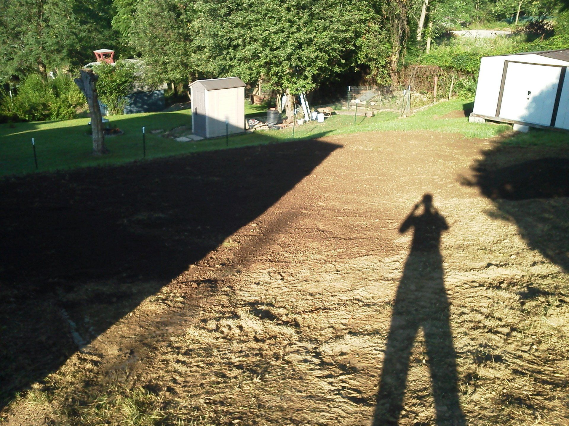 A shadow of a person is cast on a dirt field