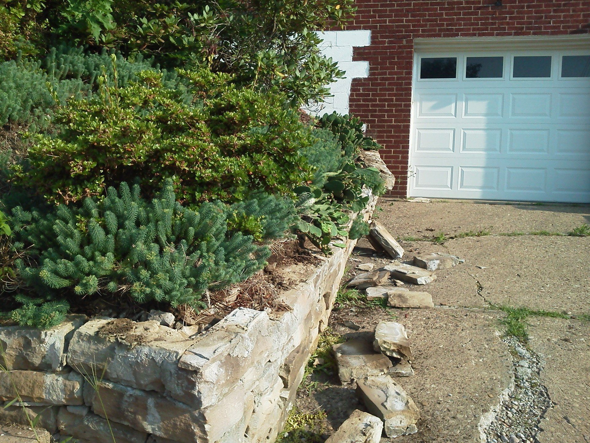 A brick house with a white garage door and a stone wall