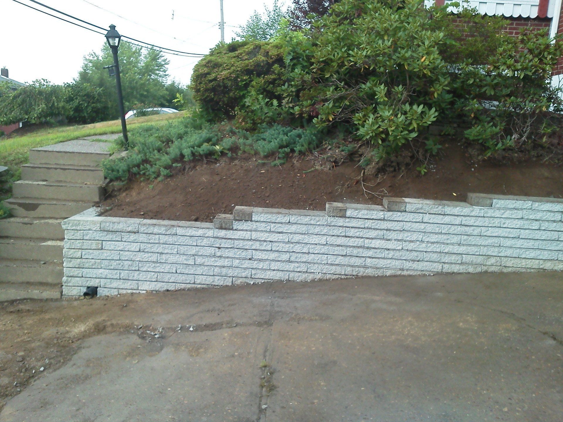 A white brick wall along the side of a driveway