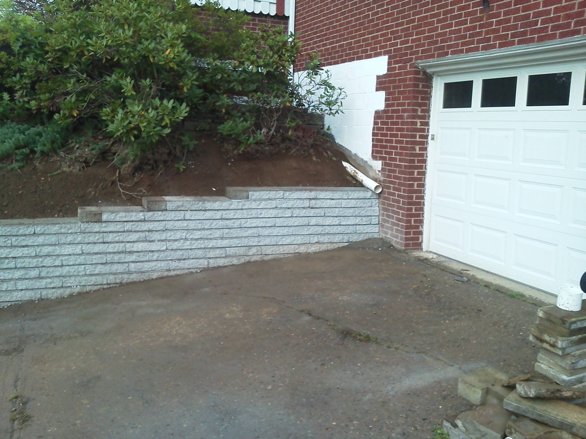 A white garage door is next to a brick wall