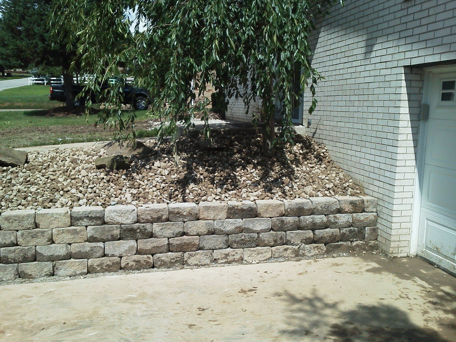 A white brick building with a stone wall in front of it