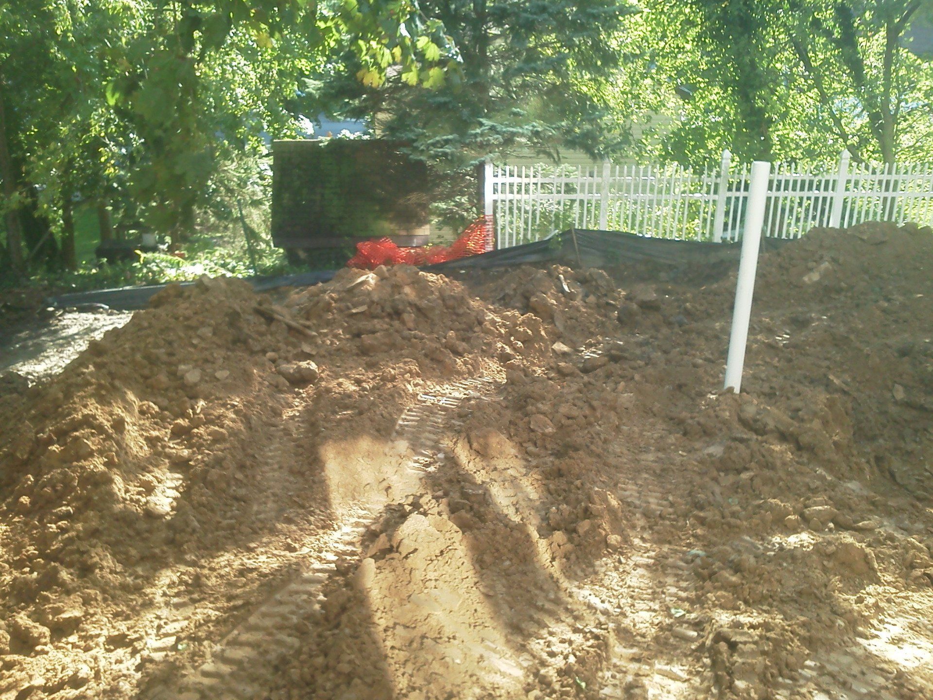 A pile of dirt is sitting in front of a white fence