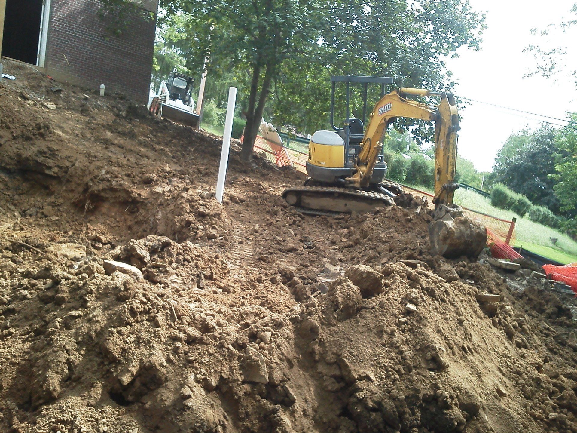 A yellow excavator is digging a hole in the dirt