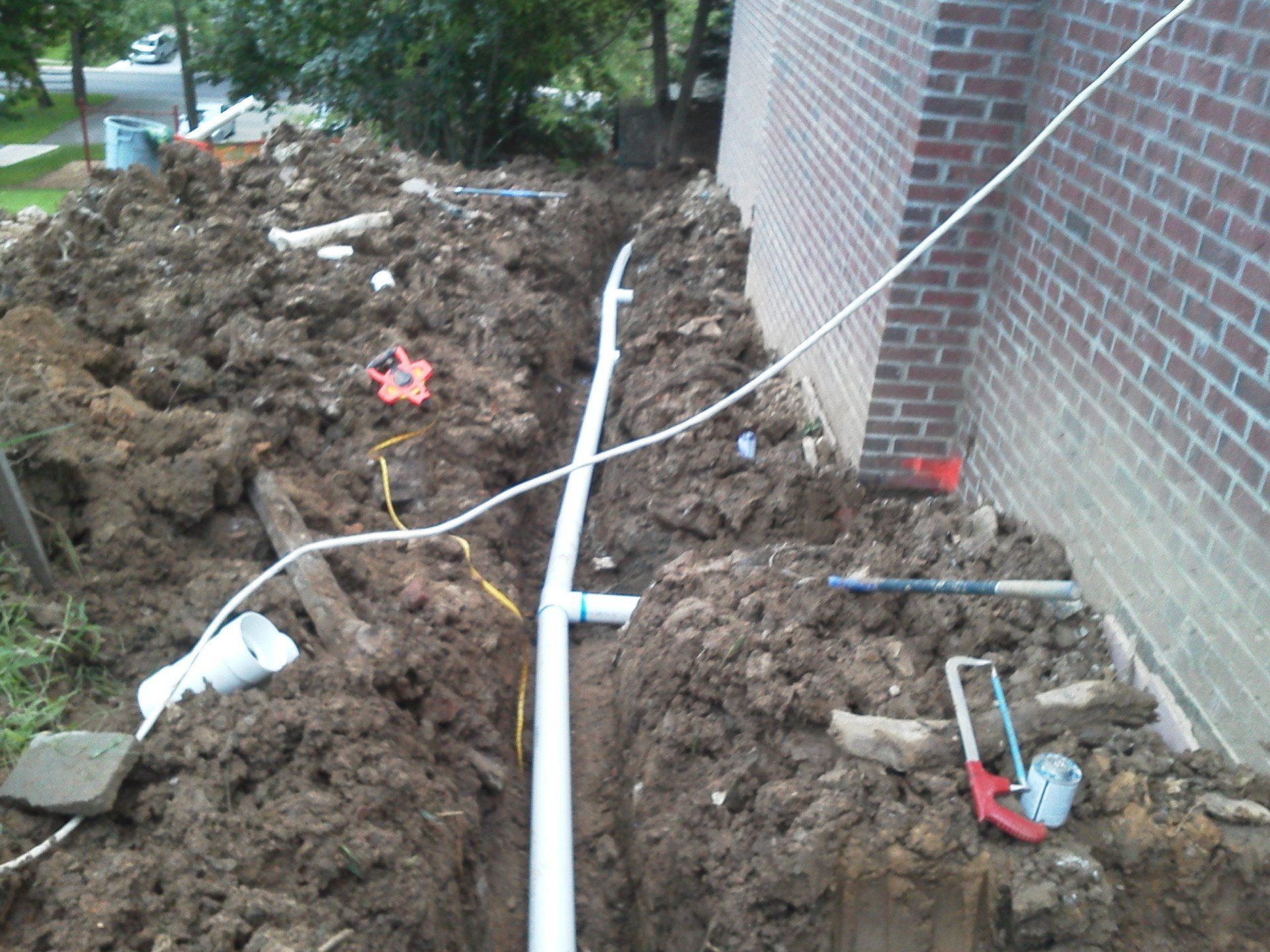 A drain pipe is being installed on the side of a house