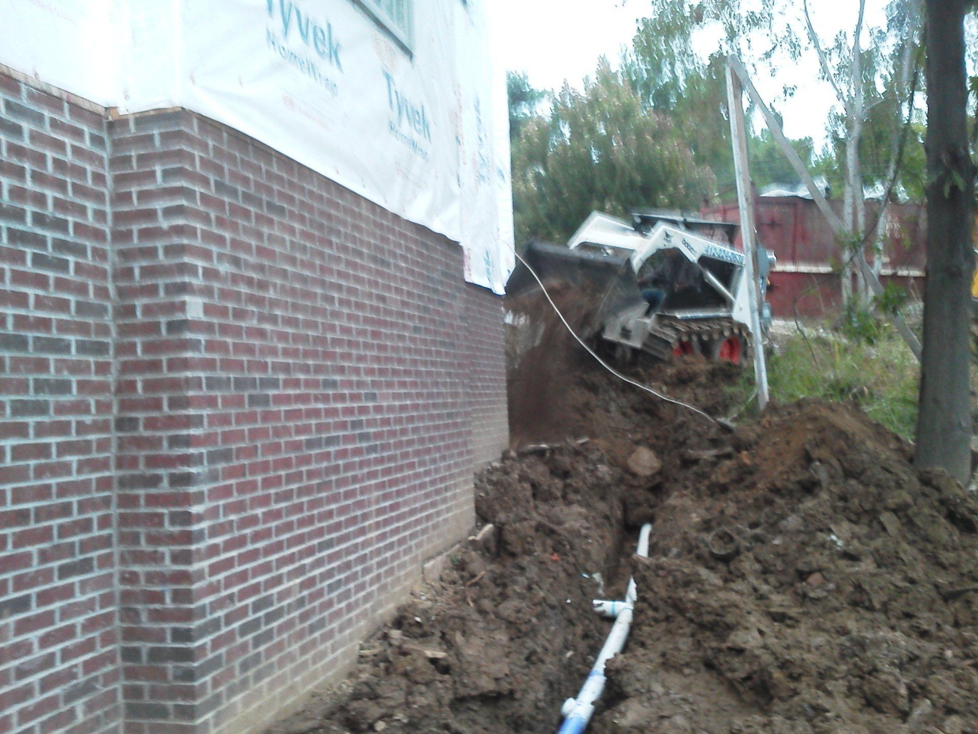 A large pile of dirt is in front of a brick wall