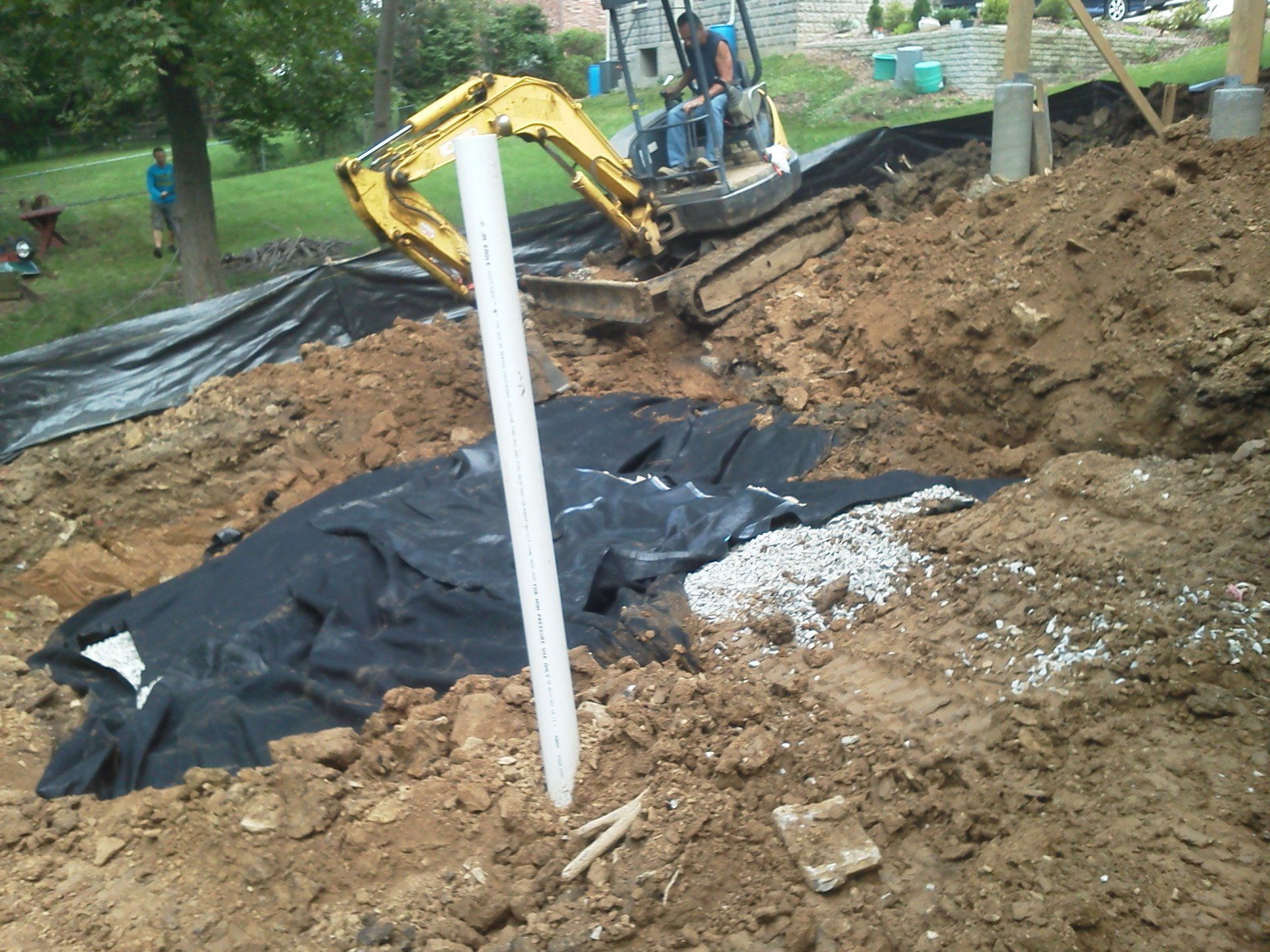 A yellow excavator is digging in a pile of dirt
