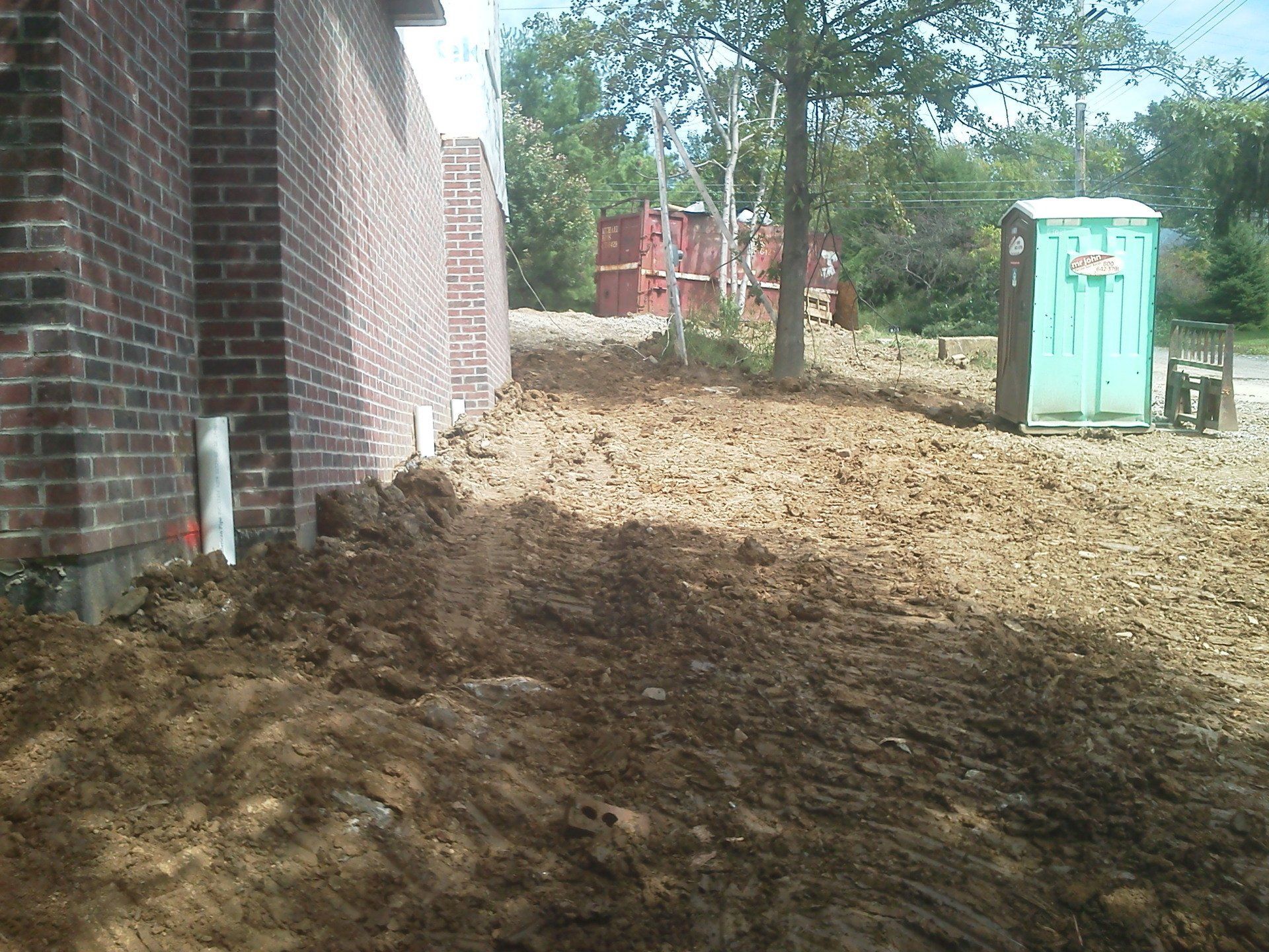 A brick building with a green portable toilet in front of it