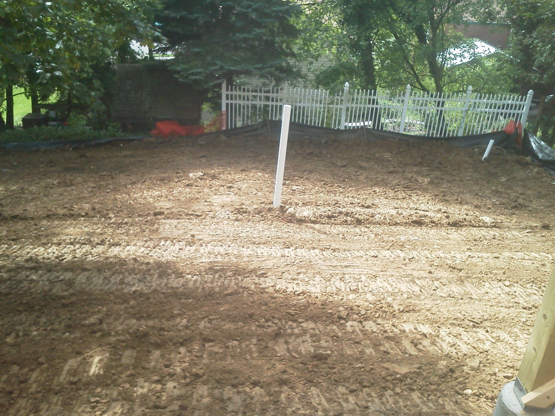 A dirt field with a white fence in the background