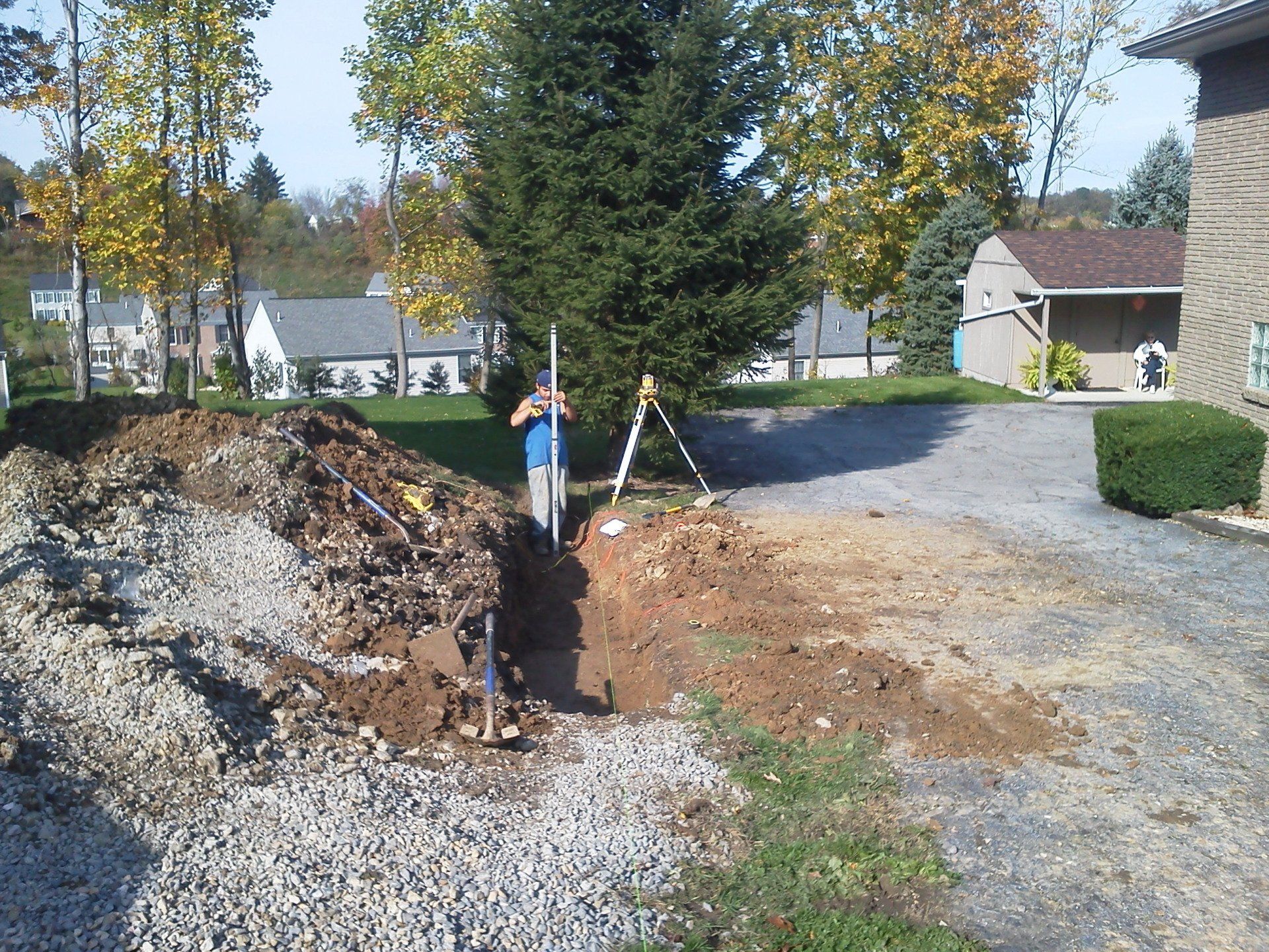 A man is standing next to a pile of dirt in front of a house