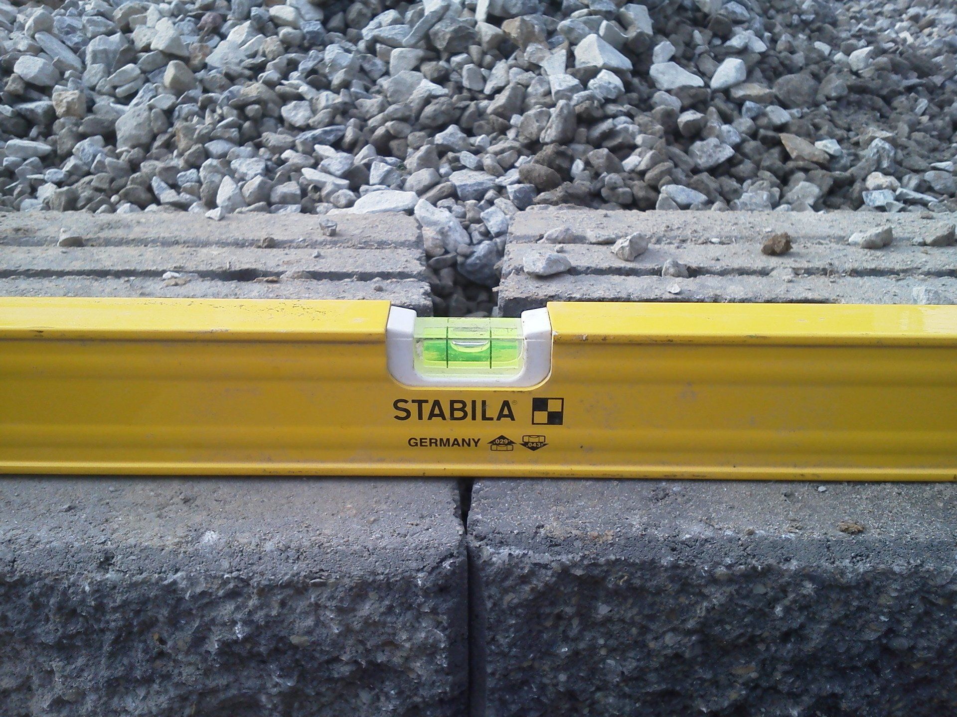 A yellow stabila level is sitting on a pile of gravel
