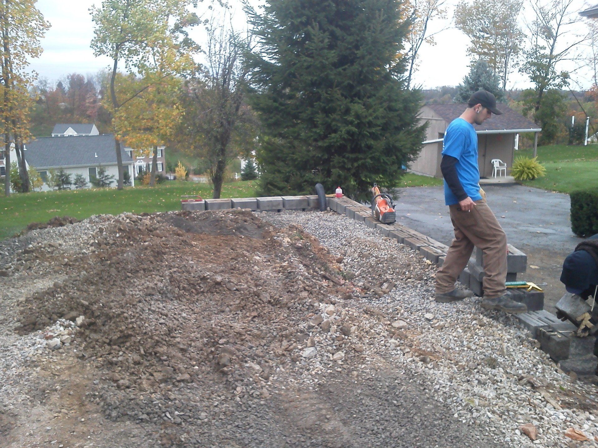 A man in a blue shirt is standing on a pile of gravel