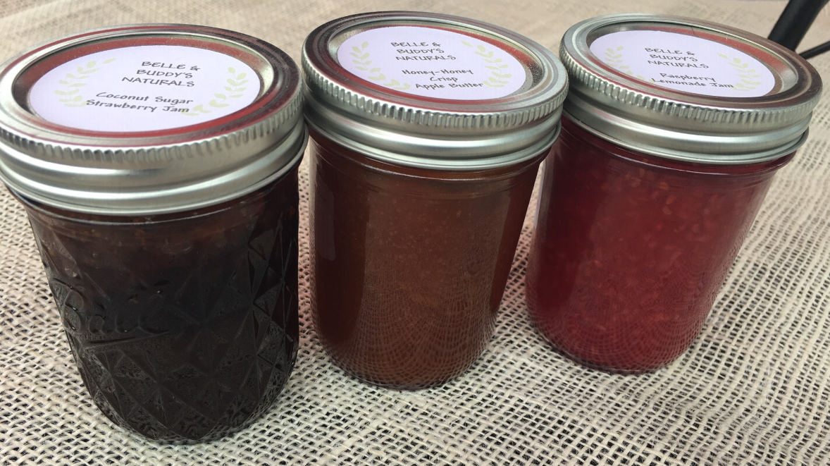 Three jars of jam are sitting next to each other on a table.