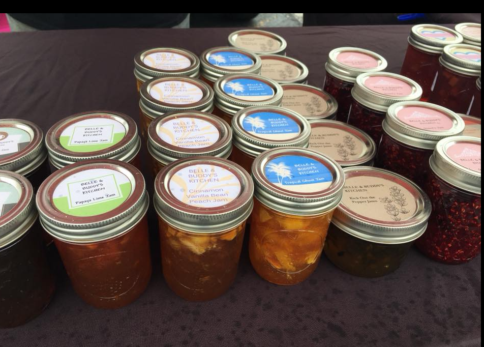Many jars of jam are lined up on a table