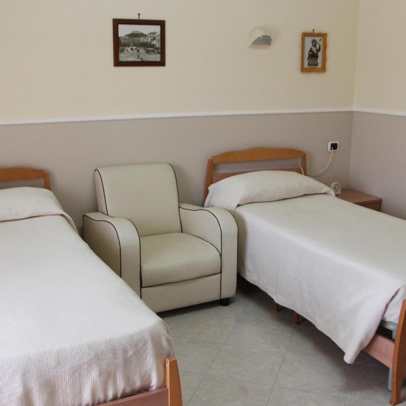 Due letti e una sedia in una stanza con quadri sul muro