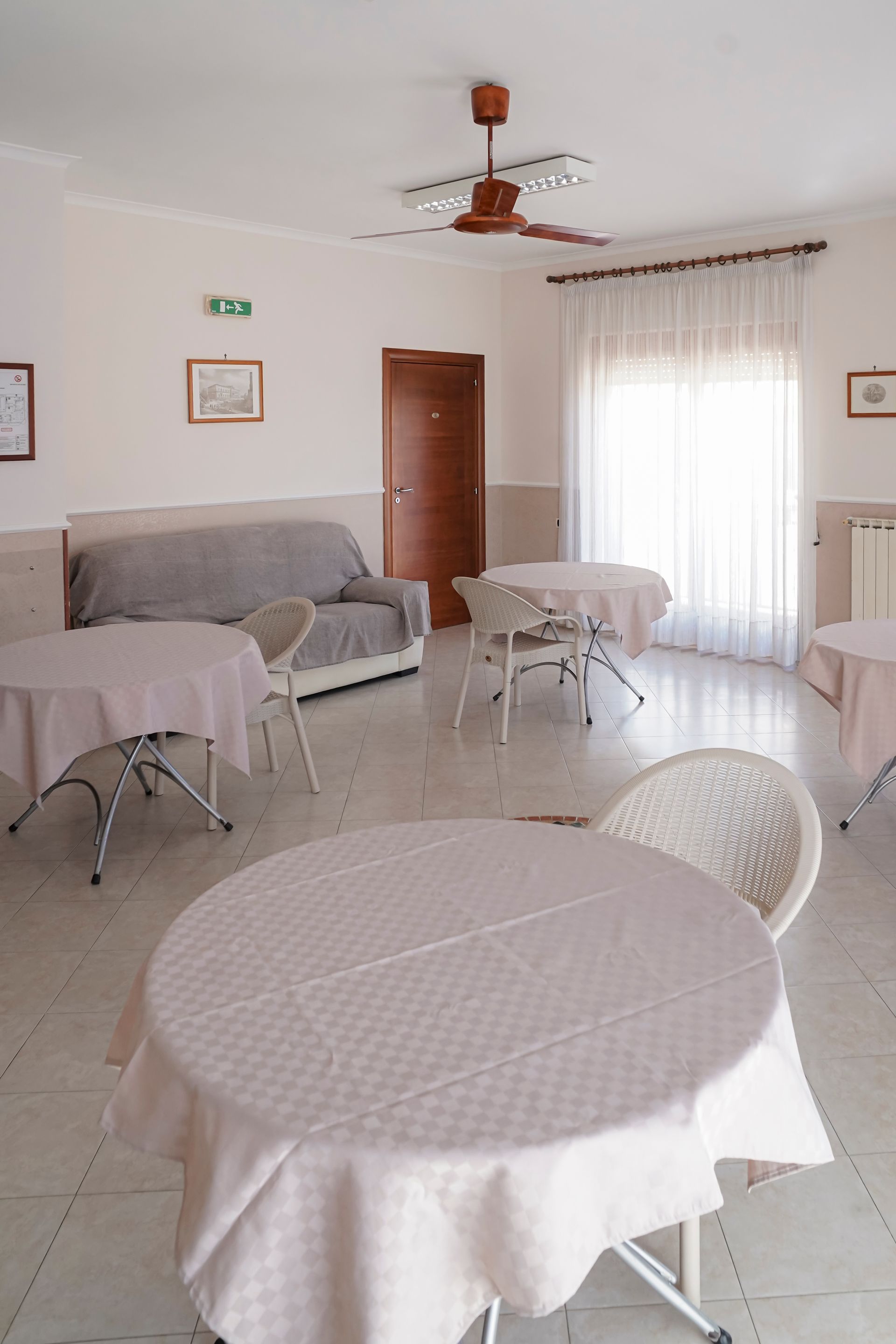 Una stanza con tavoli e sedie e un ventilatore a soffitto