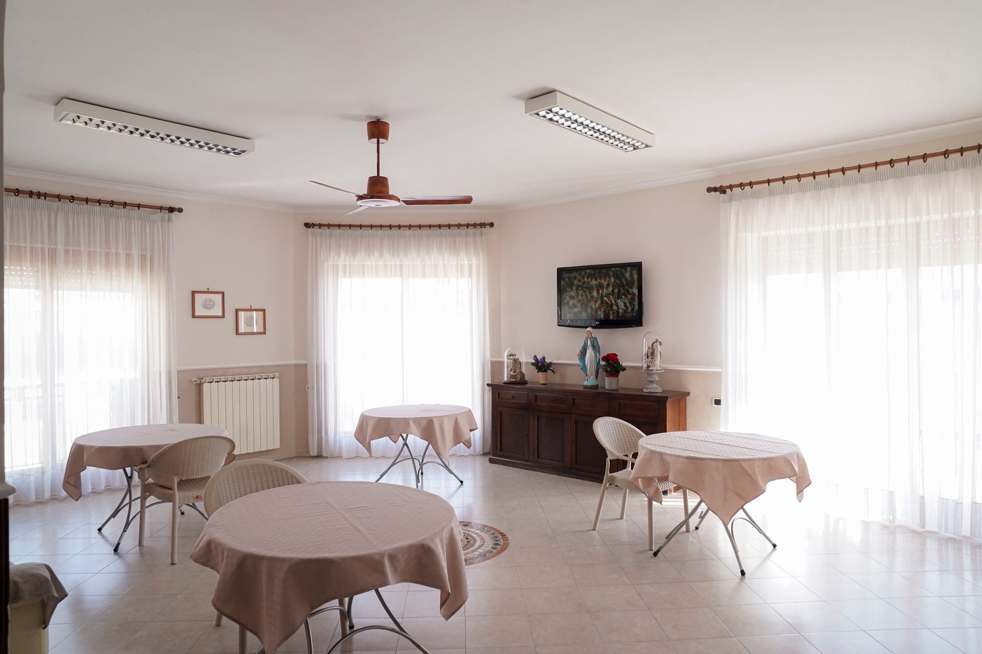 Una stanza con tavoli e sedie e una televisione sul muro