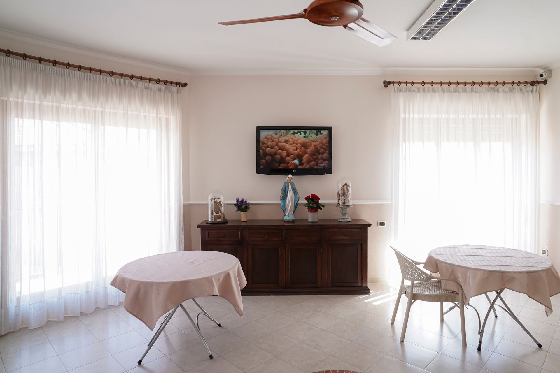 Un soggiorno con tavoli e sedie e un ventilatore a soffitto