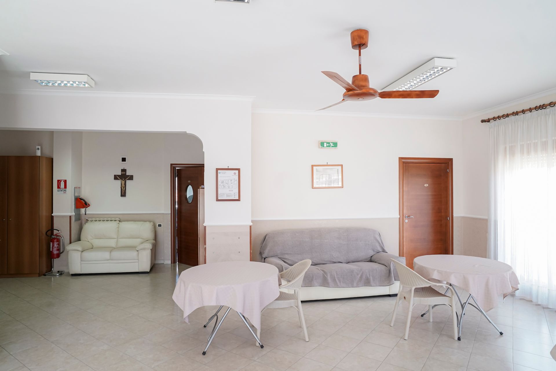 Un soggiorno con divano, tavoli e ventilatore a soffitto.