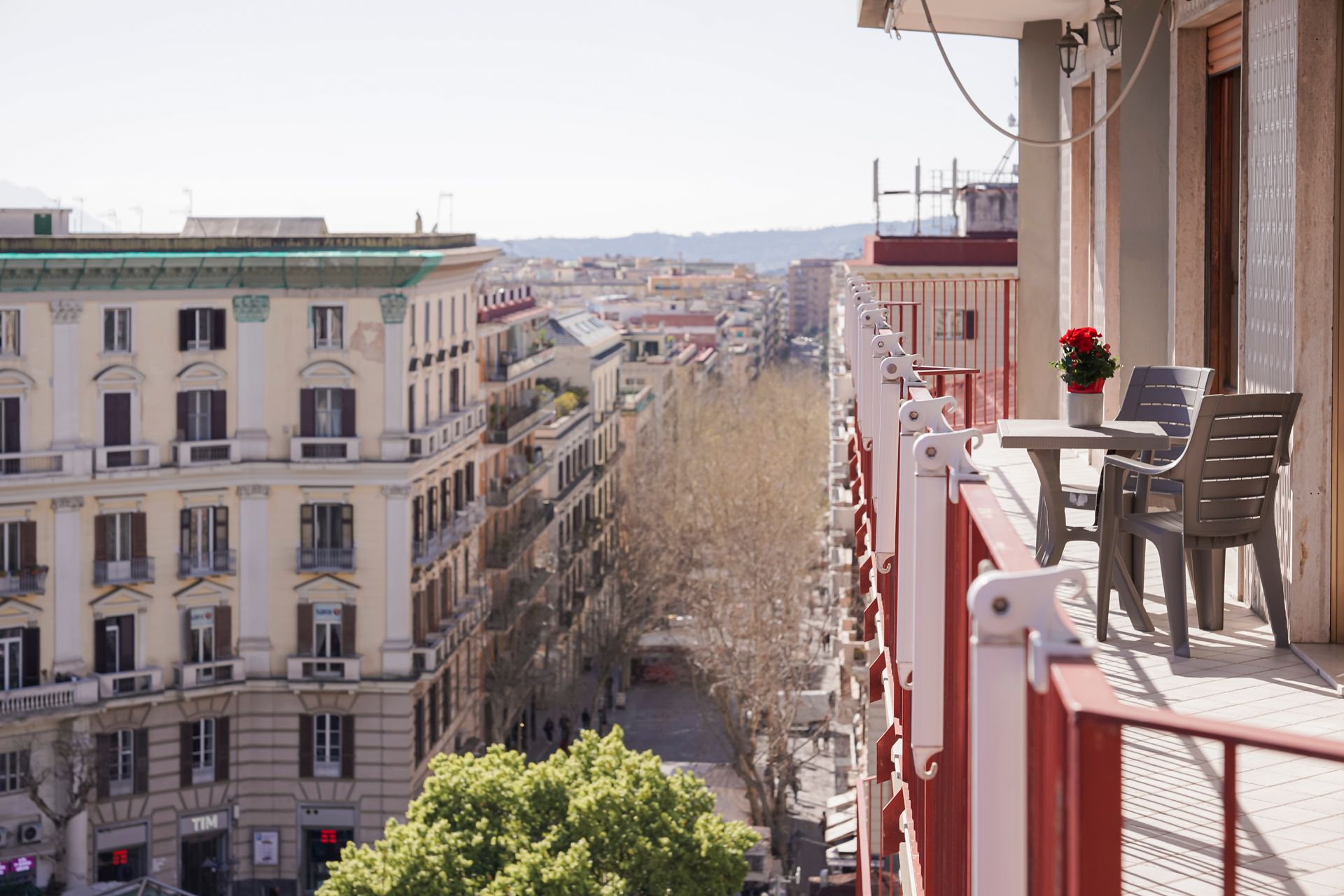 Un balcone con tavolo e sedie che si affaccia su una strada cittadina.