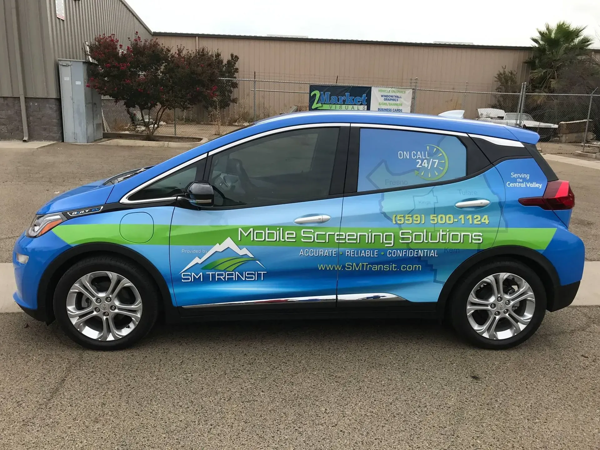 A blue and green electric car is parked in front of a building.