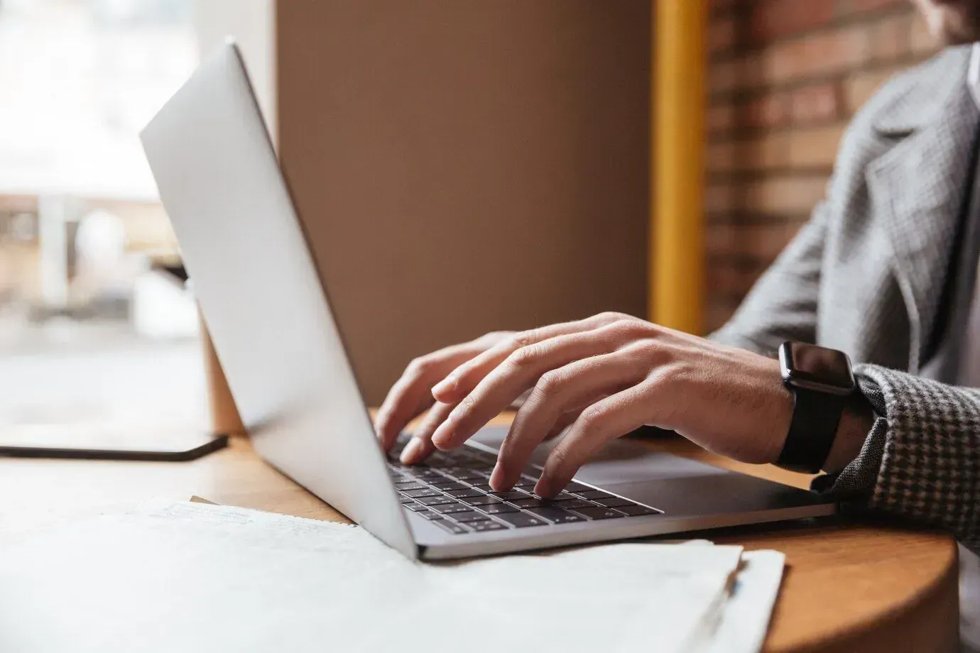 A man is typing on a laptop computer at a table.