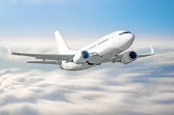 A white airplane is flying through the clouds in the sky.