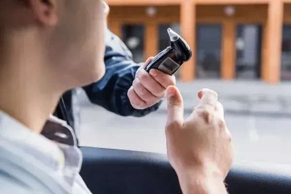 A man is holding a cell phone in his hand while sitting in a car.