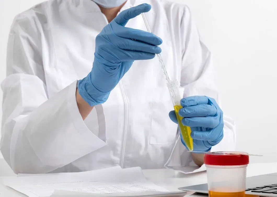 A scientist wearing blue gloves is holding a test tube.