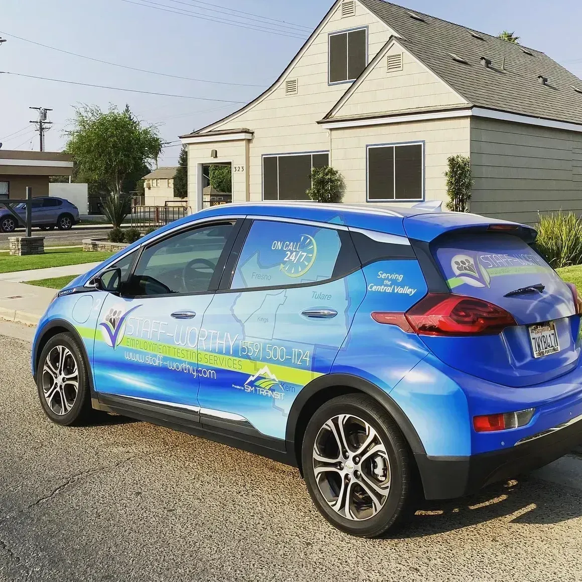 A blue car is parked in front of a house