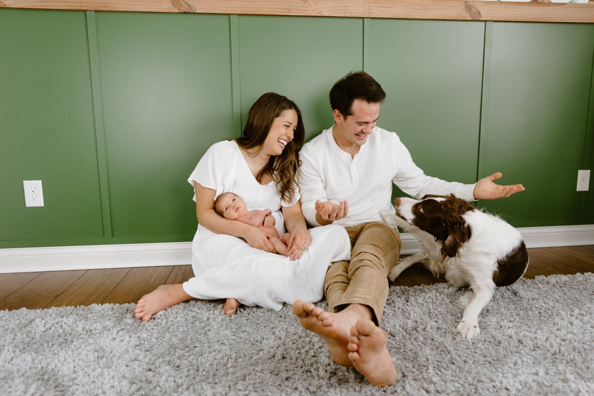 Mom and dad sit with their new baby and their dog