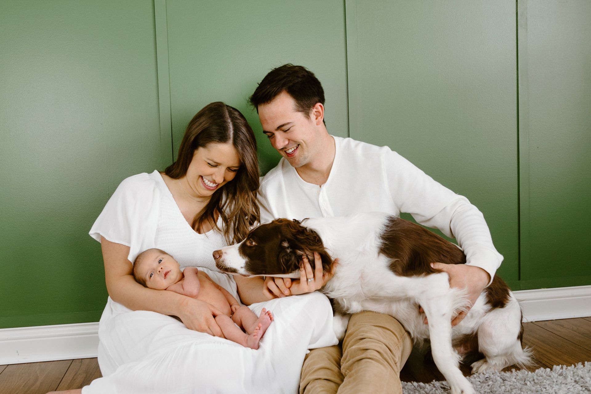 Dog looks at newborn while parents hold him