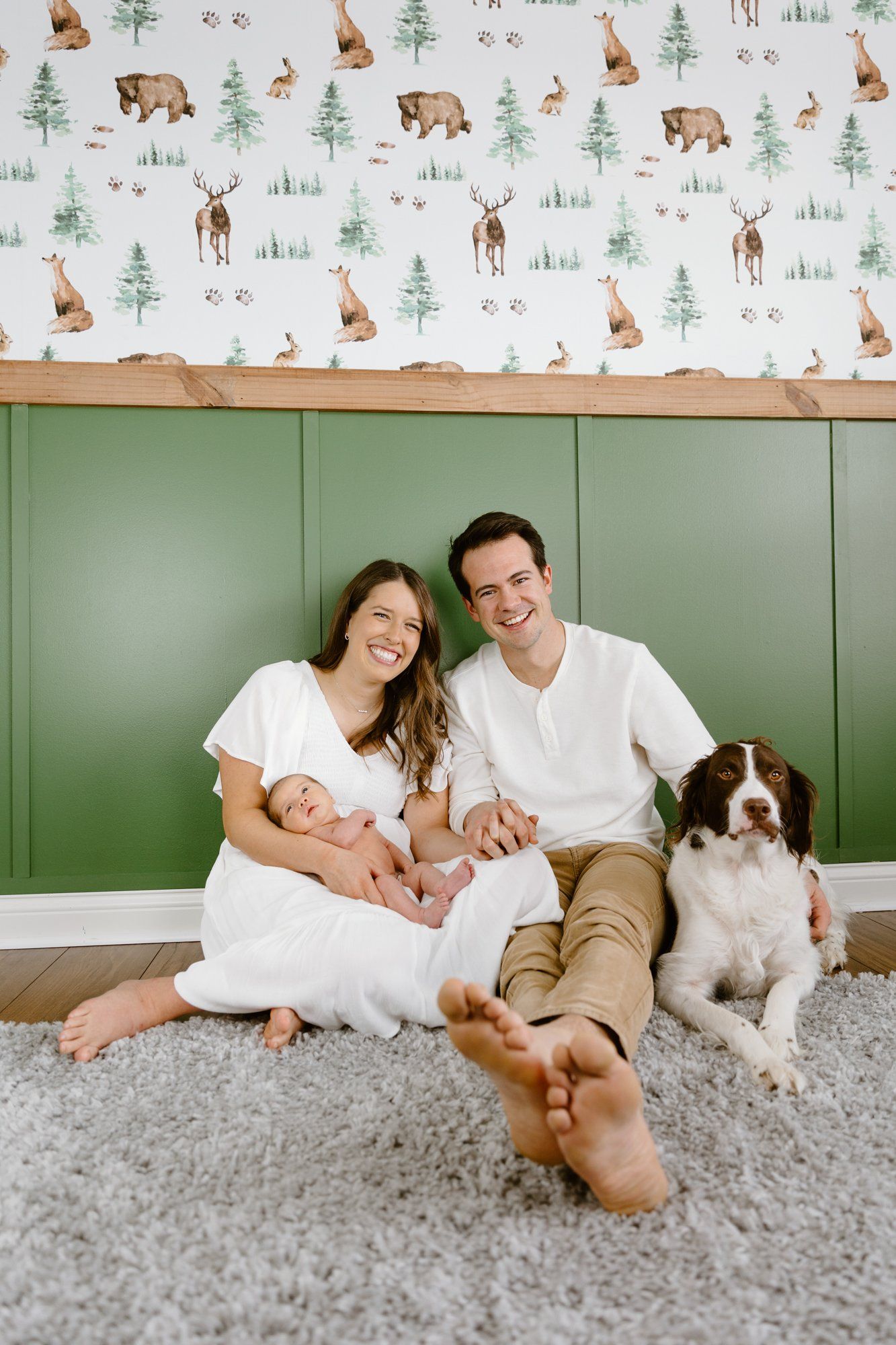 Mom and dad hold their baby in front of their nursery accent wall