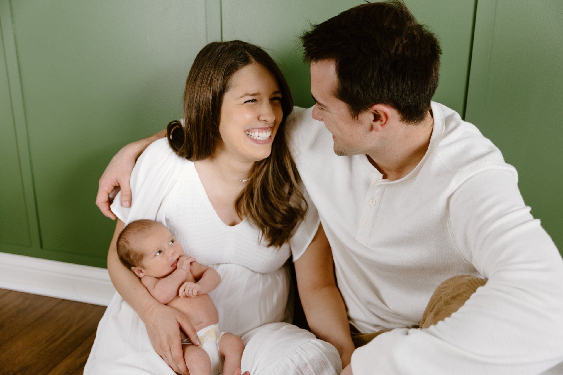 Mom and dad look at each other while holding their newborn baby