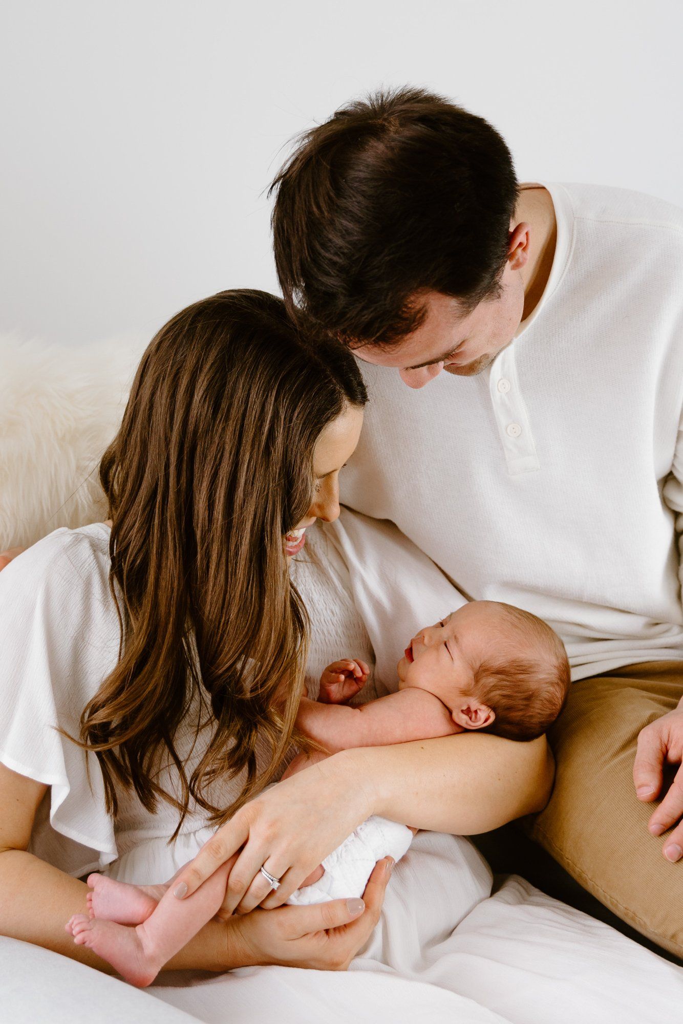 Mom and dad look at their baby while holding him