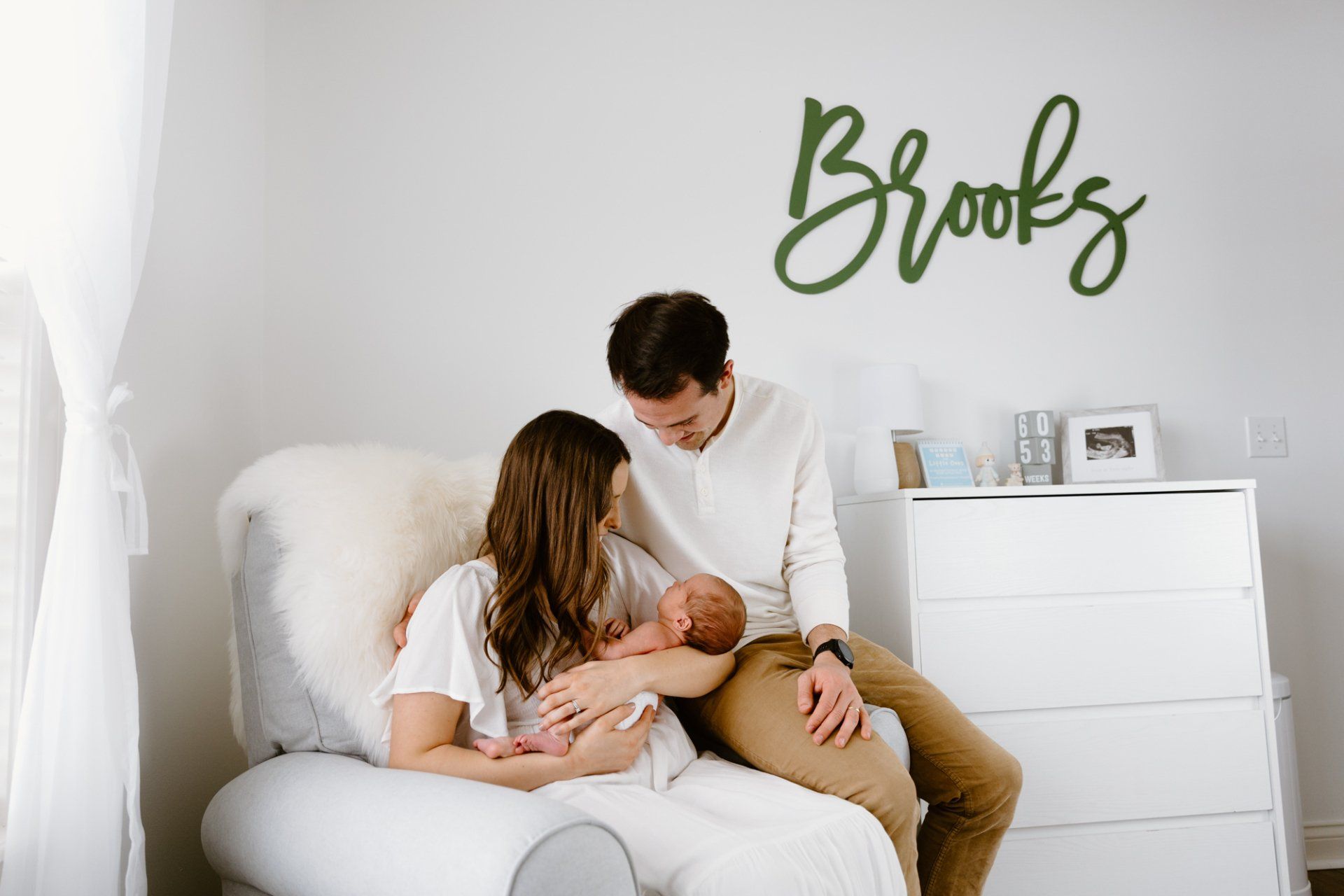 Mom and dad look at their baby while sitting in the nursery