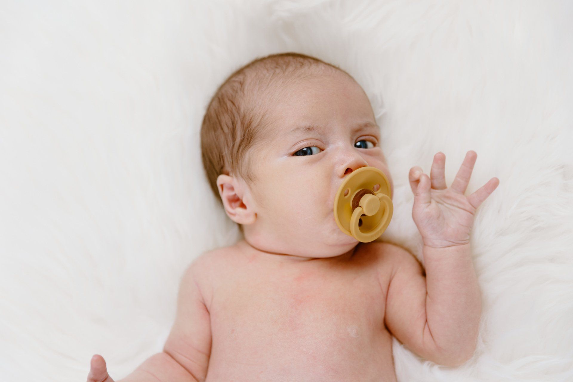 Newborn boy lays with his pacifier