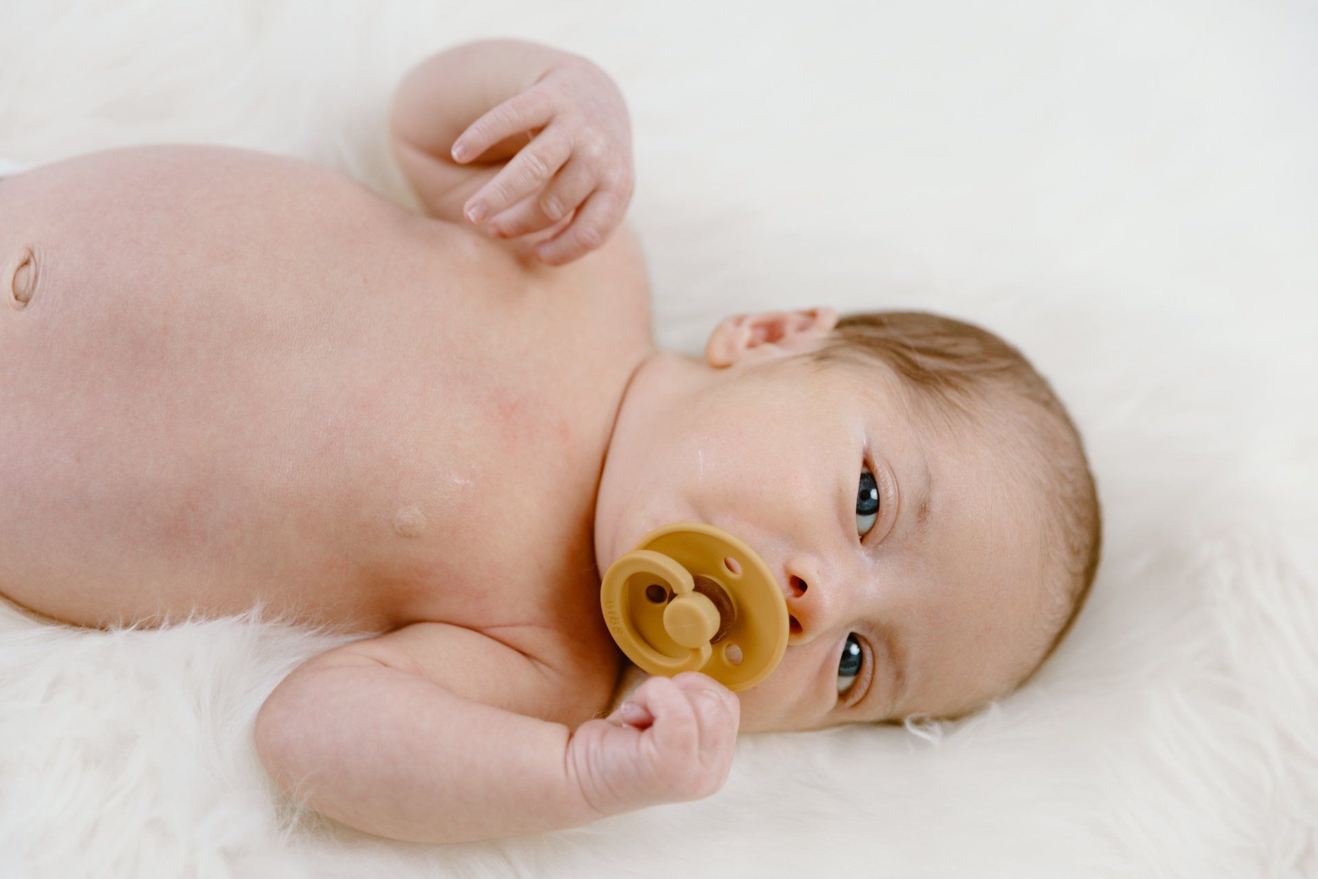Baby lays on the ground with his pacifier