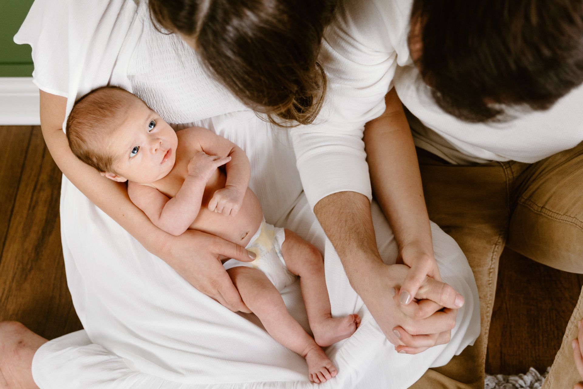 Mom and dad hold hands while holding baby