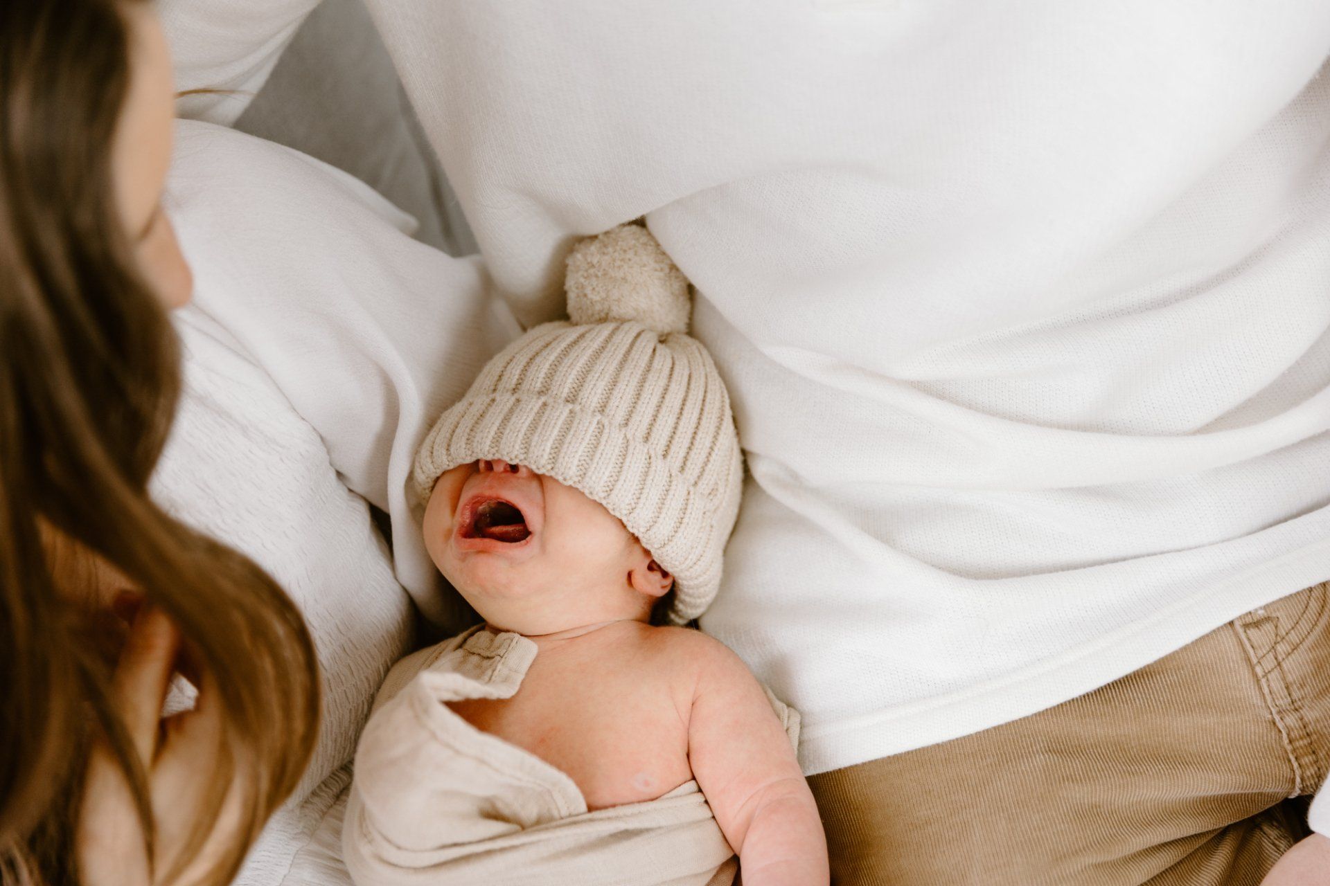 A hat covers a newborn baby's eyes