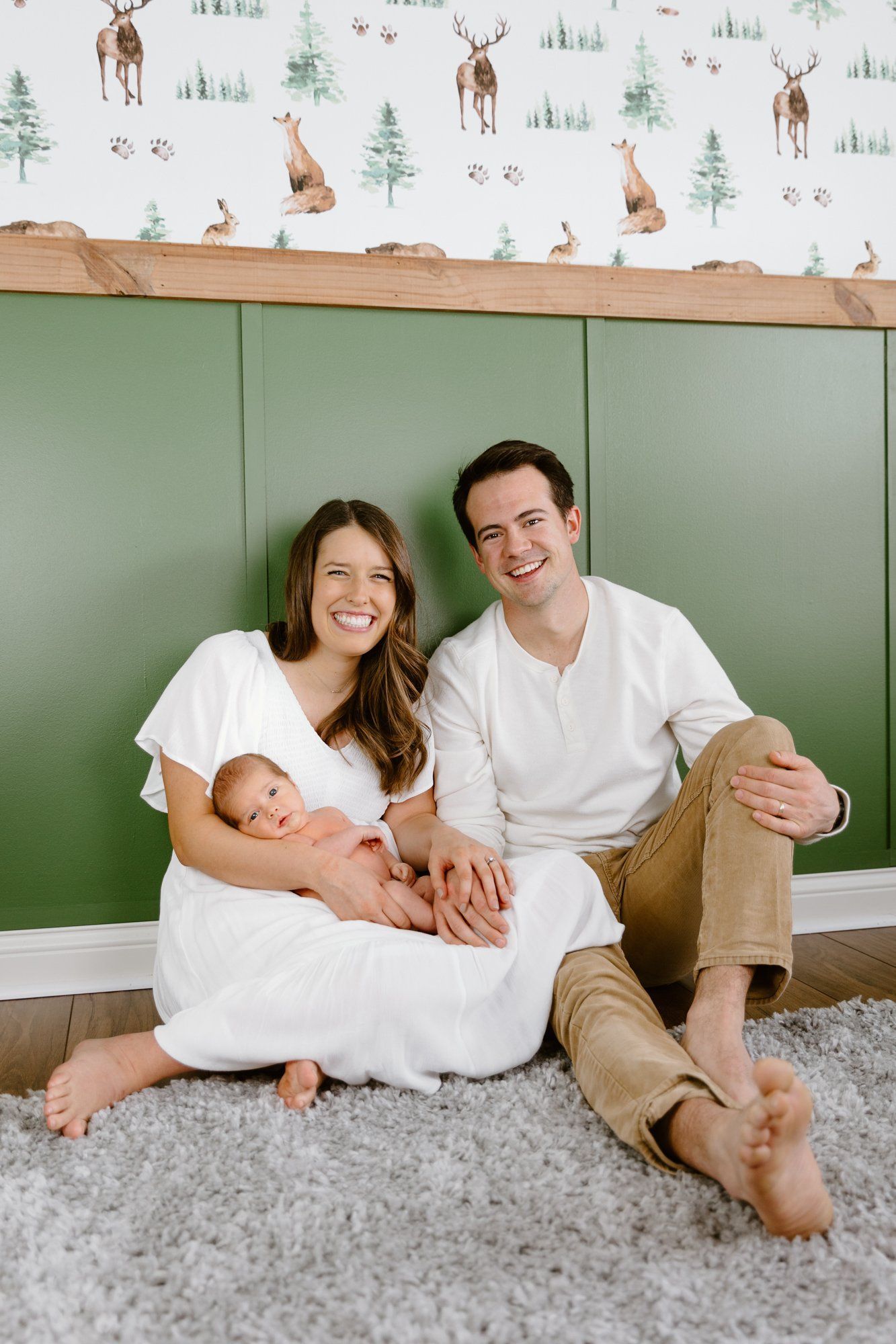 Mom and dad sit in the nursery with their baby