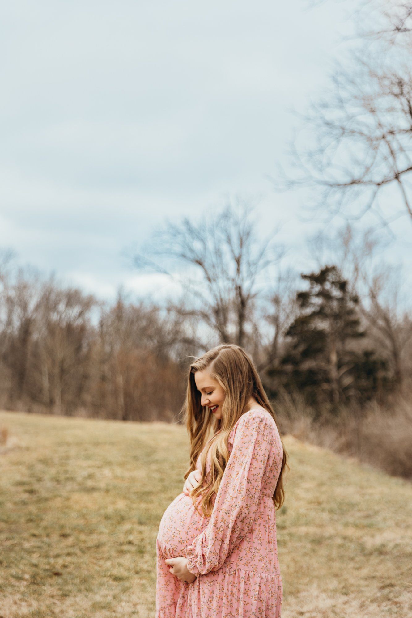Pregnant wife golds her baby bump and looks down
