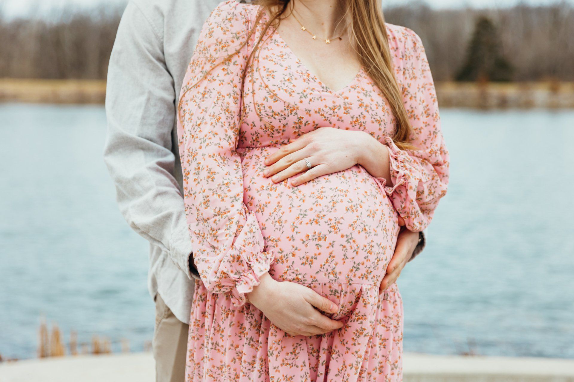 Husband hugs his pregnant wife as she holds her belly
