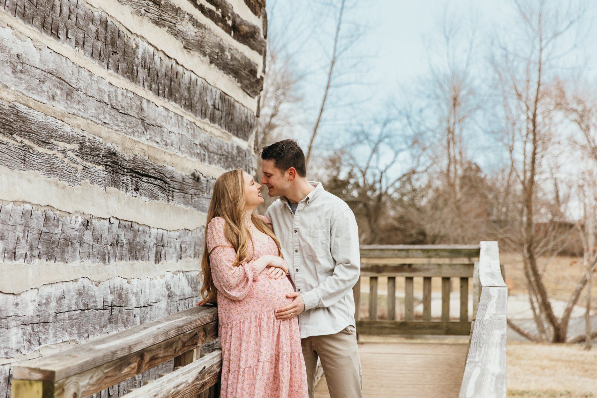 Soon to be parents kiss as they hold the baby bump
