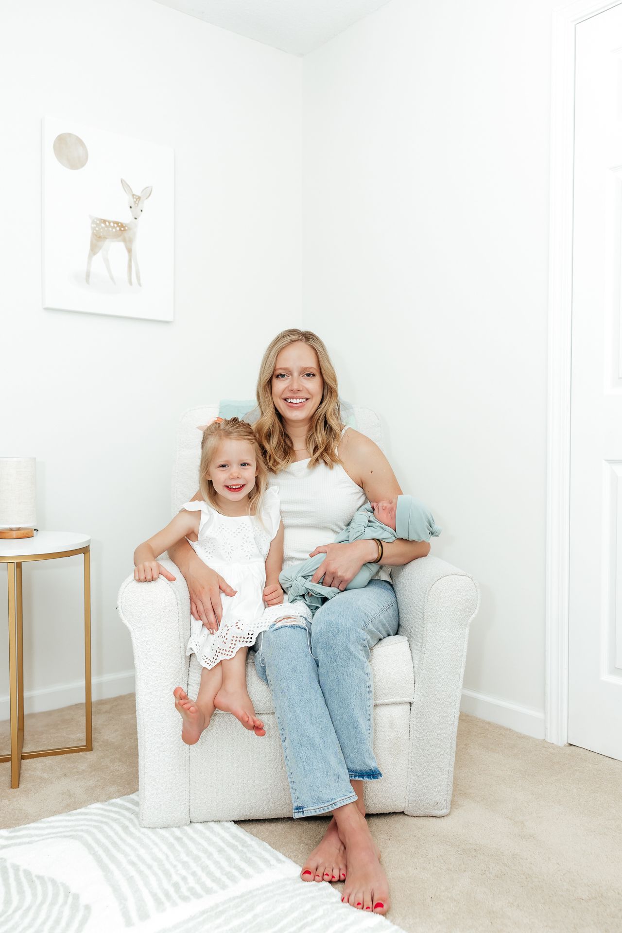 Woman seated in chair with two children in a nursery. One child is a newborn.