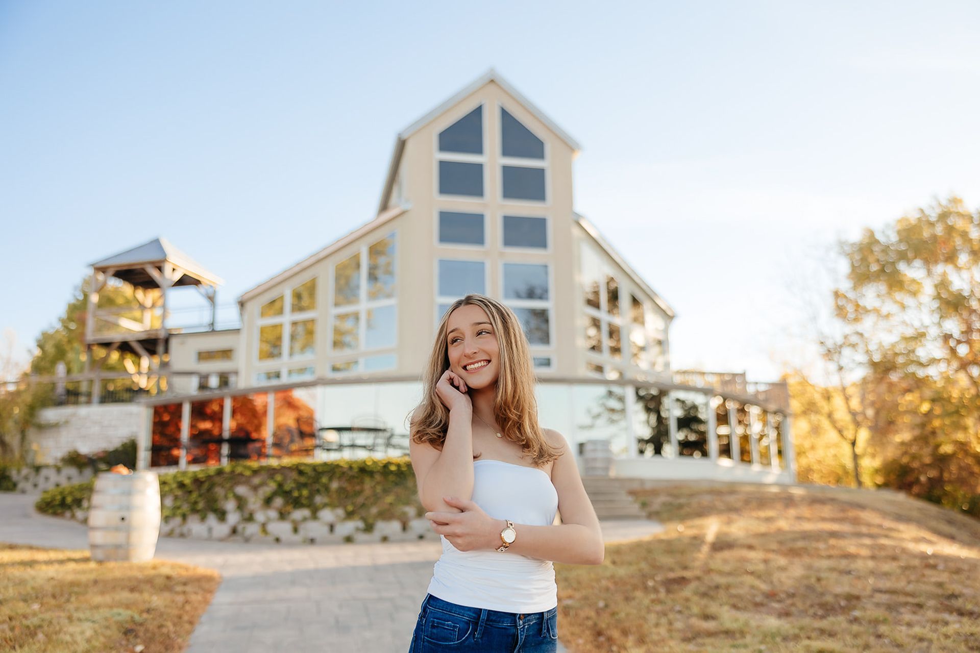 Woman smiling, standing outdoors in front of a modern building with large windows.
