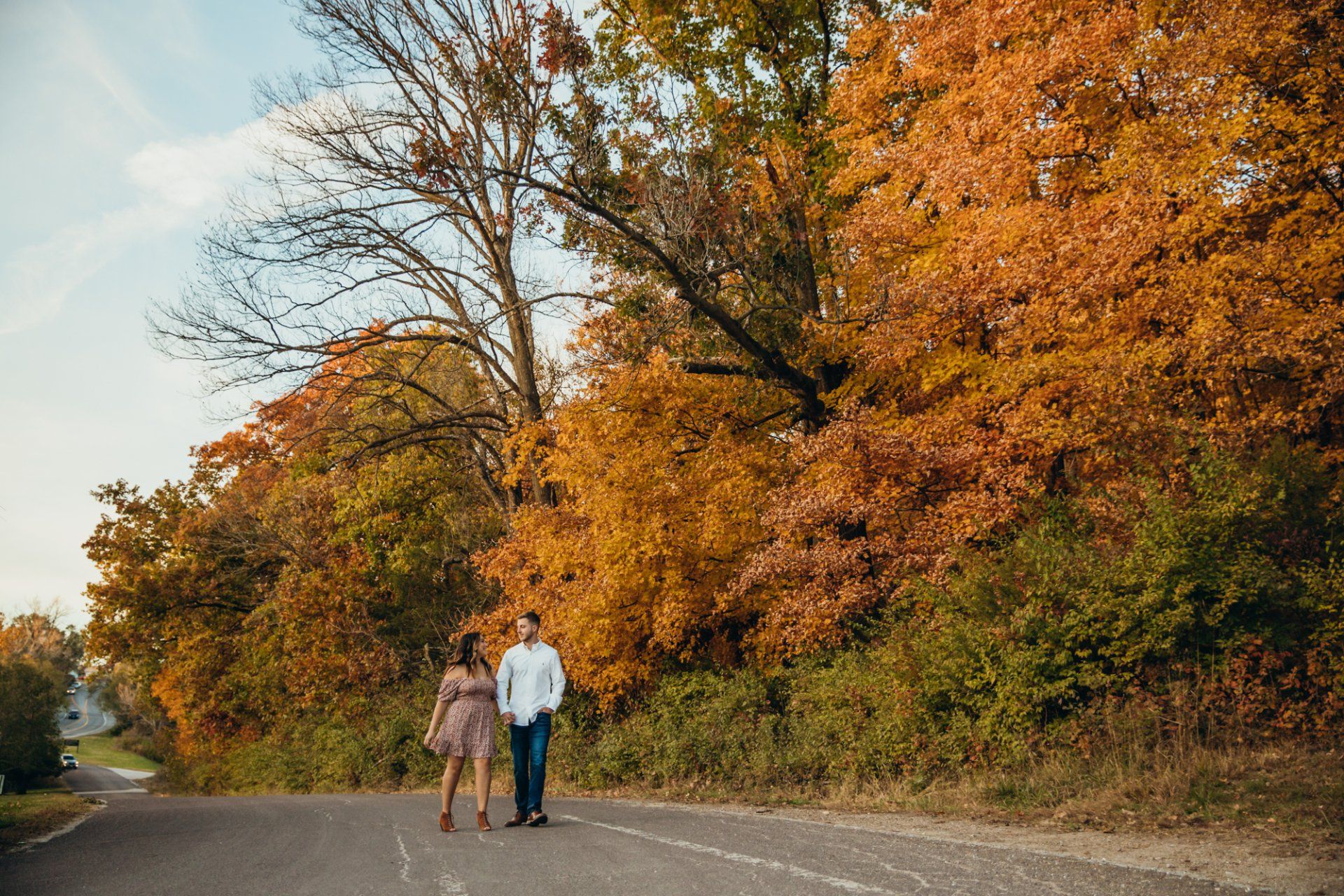 Engaged couple walk while holding hands and looking at each other